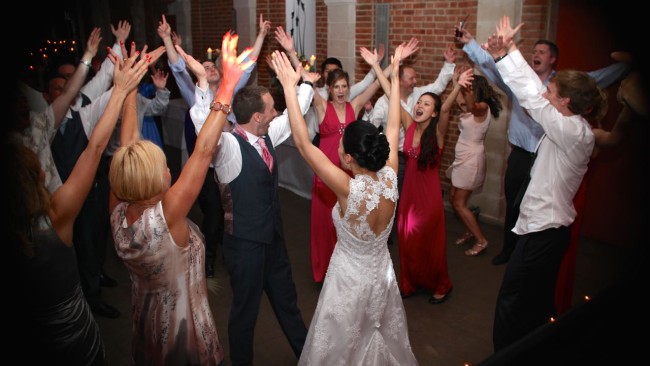 bride and groom dancing with their guests at the great barn in Great Fosters