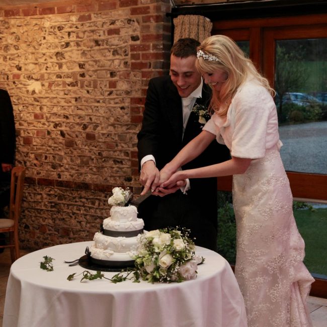 Tessa and Michal cutting the cake at their wedding in Upwaltham Barns