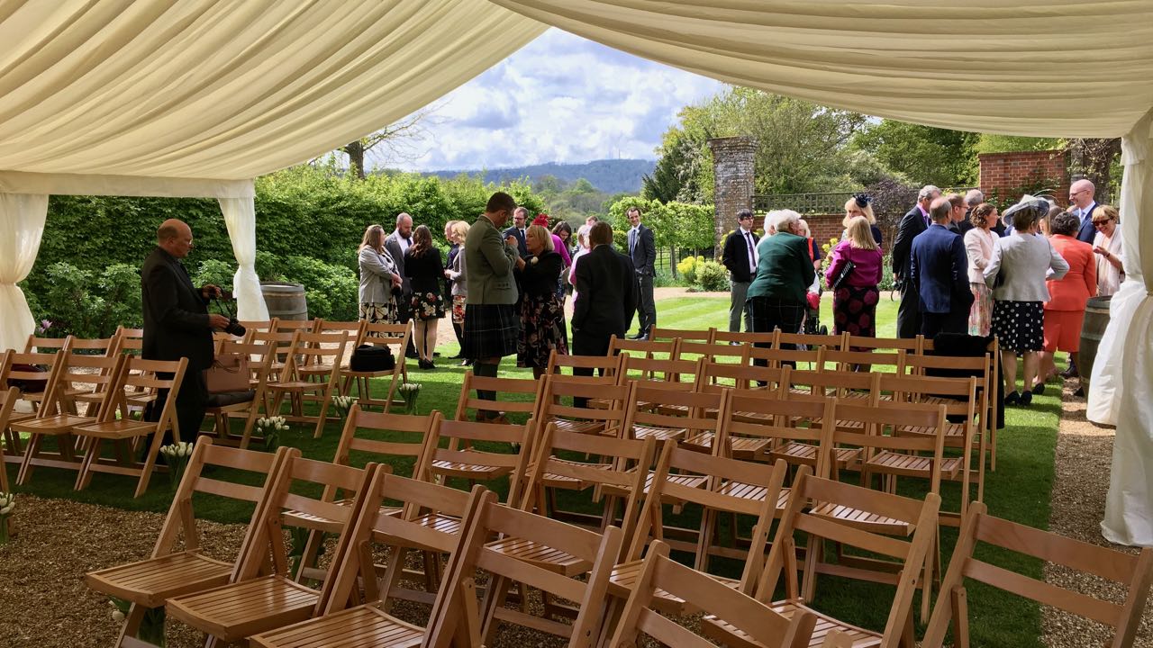 wedding guests gathering in the sunshine in Bignor Park's greek loggia